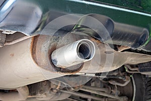 Bottom view of the exhaust pipe of the car, rusty, dusty parts and fixtures