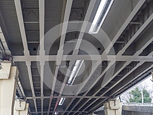 Bottom view of a fragment of a gray iron automobile overpass on concrete supports