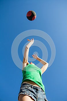 Bottom view of a girl in a jump throws a basketball over the blue sky, sports concept