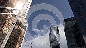 Bottom view of the glass skyscrapers of the business district against blue cloudy sky. Action. Beautiful commercial