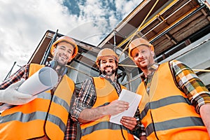 bottom view of group of builders with blueprint and tablet looking at camera