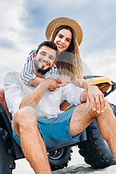 bottom view of happy young couple sitting on ATV in front of