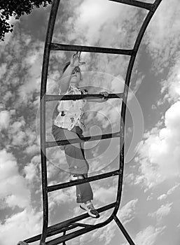 Bottom view of the little girl climbing the stairs on the sky background.