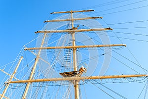 Bottom view of the mast, sail yards with the lowered sails and rigging of a sailing ship against a clear sky