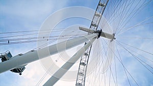 Bottom view of modern Ferris wheel on blue sky background. Action. Ferris wheel doesn`t work on clear day. Many lines