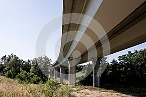 Bottom view of modern highway bridge with concrete pillars as a way of transportation