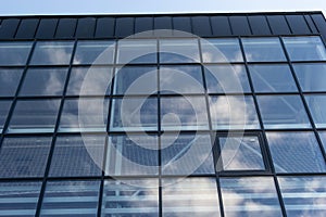 Bottom view of a modern skyscraper building with glass window against sky background for promotional content. Contemporary