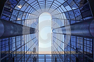 Bottom view through a modern tall skyscraper up to the blue sky. Abstract fragment of architecture
