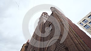 Bottom view of red brick Catholic Church. Action. Old Church in modernist style stands on background cloudy sky photo