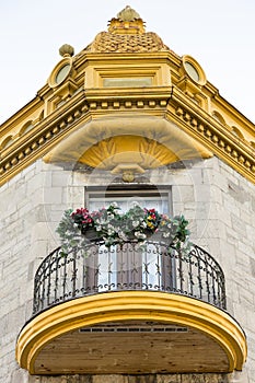 Bottom view of round wood and metal balcony and ornate golden cornice