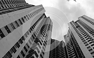 Bottom view of skyscraper building against gray sky and clouds. Looking up view in apartment building in the city. Real estate