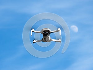 Bottom view of a small white drone with camera flying with its propellers out of focus due to speed