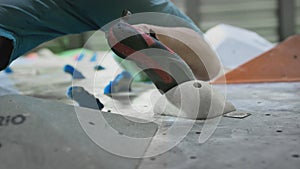 Bottom view: A sporty Caucasian man climbs a bouldering wall. Moves legs on ledges. Practices climbing on an artificial