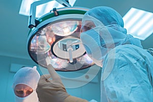 Bottom view of surgeons in the operating room, in sterile masks, preparing for surgical intervention, arms raised up, in sterile