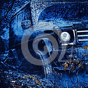 Bottom view to big offroad car wheel on country road and mountains backdrop. Jeep crashed into a puddle and picked up a