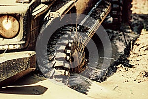 Bottom view to big offroad car wheel on country road and mountains backdrop. Off-road vehicle goes on mountain way