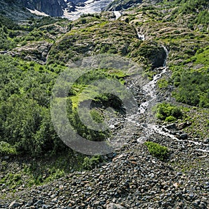 A bottom view of a waterfall flowing from a glacier in a mountain gorge. Mountain river in the Caucasus. Picturesque
