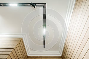 Bottom view of white ceiling with line lamp in the middle. Walls with wooden effect tiles