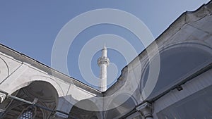 Bottom view of a white temple details with arches and long spire. Action. Beautiful historic building on blue sky