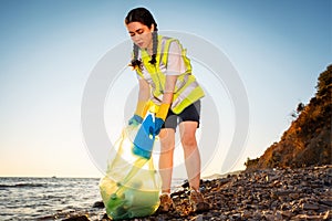 Bottom view of young woman volunteer picking up garbage at beach. Concept of ocean& x27;s pollution and environmental