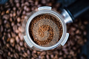 Bottomless filter with grind beans on a wooden black table. Roasted coffee beans. Espresso coffee extraction. Prepare of espresso. photo