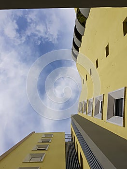 Bottow view of yellow residencial building against blue cloudy sky