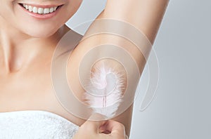 After the botulinum toxin injection procedure. A woman holds a feather in the skin in the armpits, showing dryness and lack of