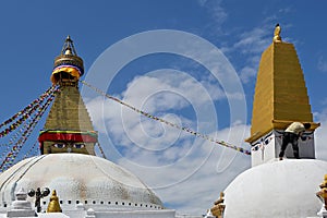 All-seeing Eyes of Buddha overseeing Boudhanath, while a worker applies paint on a stupa's spire, Kathmandu