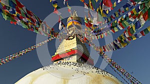 Boudhanath stupa in Kathmandu, Nepal. Camera moves between Buddhist flags swaying in the wind, pigeons sit on the dome