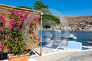 Bougainvillea flowers in street cafe, located near blue lagoon at Symi island, Greece