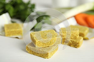 Bouillon cubes and other ingredients for soup on white wooden table, closeup