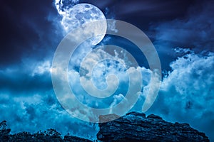 Boulder against blue sky with clouds and beautiful full moon at