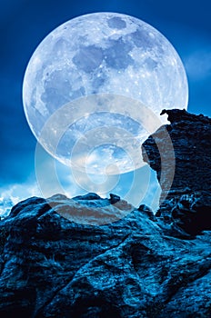 Boulder against blue sky with clouds and beautiful full moon at