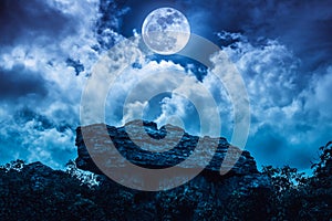 Boulder against blue sky with clouds and beautiful full moon at