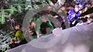 Boulder climbing in the woods. climber trying to climb on a boulder and friends insure the bottom.