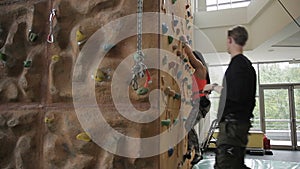 Bouldering instructor shows woman moving on climbing wall.