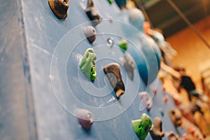 Bouldering wall knobs. Young boys practice climbing skills in blurred background