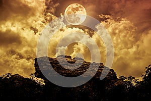 Boulders against sky with clouds and beautiful full moon at nigh