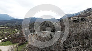 Boulders expanse at the foots of mountain range. Shot. Aerial view of a wild valley covered by stones, greenery and