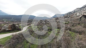 Boulders expanse at the foots of mountain range. Shot. Aerial view of a wild valley covered by stones, greenery and