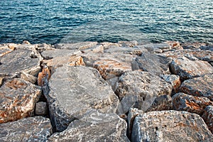 Boulders are large, artificial reinforcement, piled on seashore in front of water