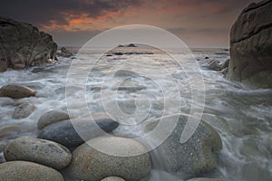 Boulders on Porth Nanven beach looking towards the Brisons at sunset Cot Valley near St Just Cornwall