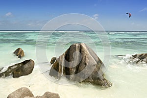 Boulders rocks and man doing kitesurf in Anse Source d'Argent beach, La Digue island, Seychelles