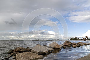 Boulders in the water of the Wolderwijd with the monument to Allied airmen near Harderwijk, Netherlands in the background photo