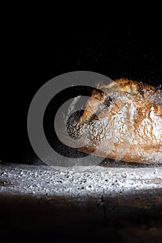 Boule or rustic loaf of french bread in motion on an old wooden table