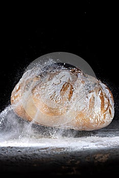 Boule or rustic loaf of french bread in motion on an old wooden table