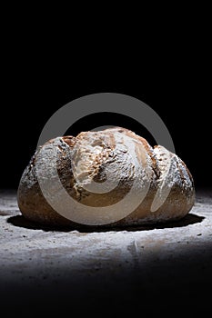 Boule or rustic loaf of french bread in motion on an old wooden table