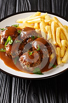 Boulet a la liegeoise or boulet sauce lapin is a Belgian dish of meatballs in apple sauce and French fries closeup in the plate.