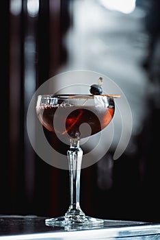 The Boulevardier Cocktail with orange chips on top. On a bar desk