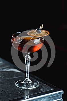 The Boulevardier Cocktail with orange chips on top. On a bar desk